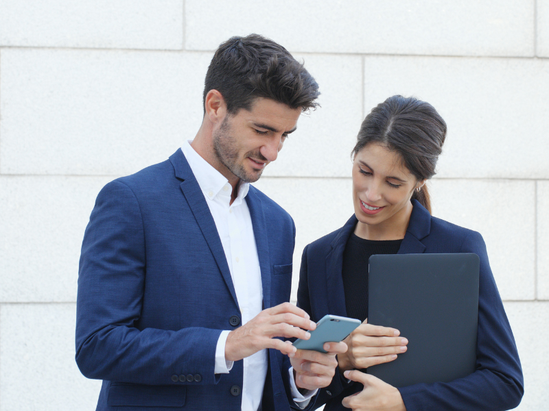 two professionals chatting outside looking at a phone